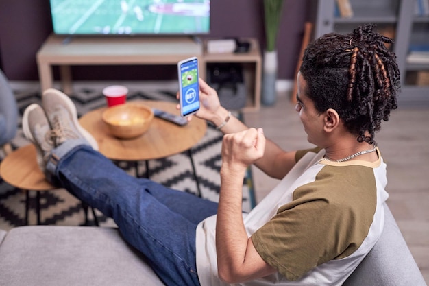 Man watching football match at home and winning online bet