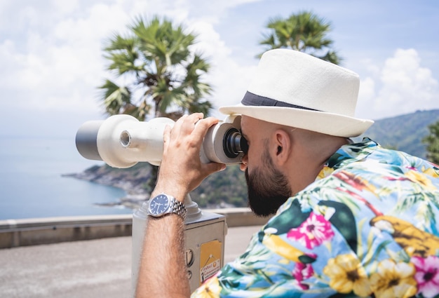 Man watching through binoculars telescope standing on observation point