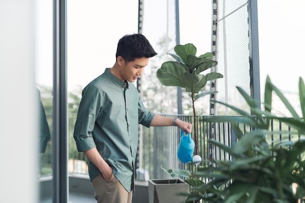 Man watering house plants on the balcony