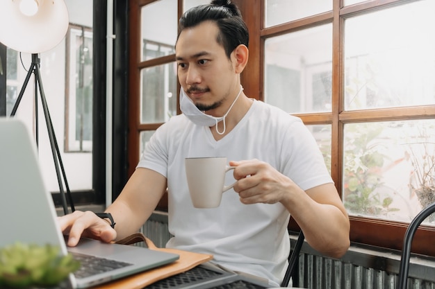 Man wear mask while work with his laptop in the cafe