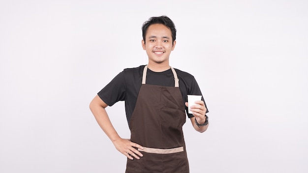 The man wearing the apron stands on a white background holding a glass