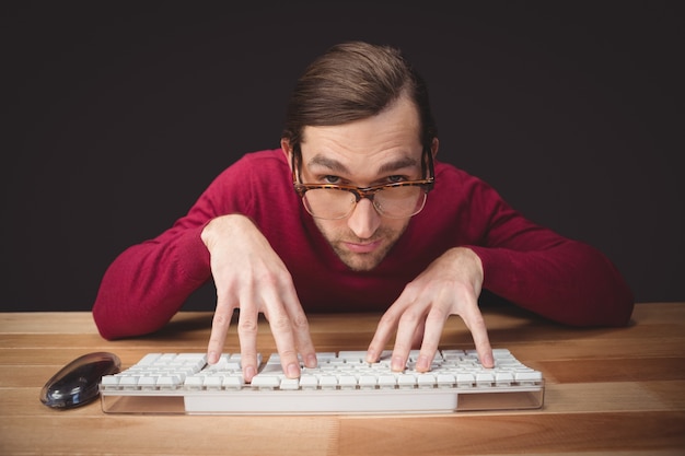 Photo man wearing eye glasses typing on computer keyboard