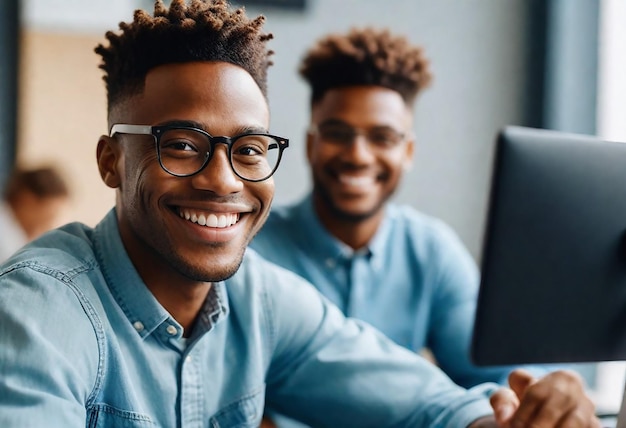 a man wearing glasses sits in front of a computer with a smile that says  happy