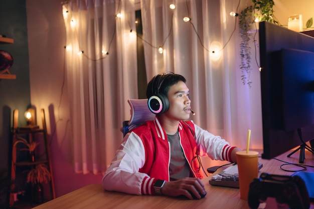 a man wearing headphones sits at a desk with a computer mouse on his head