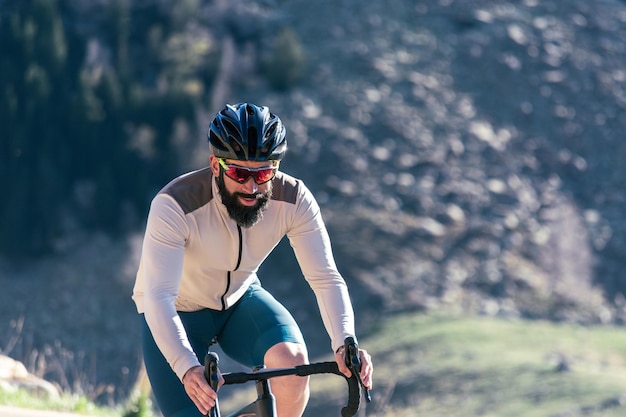 Photo a man wearing a helmet and sunglasses is riding a bicycle on a mountain