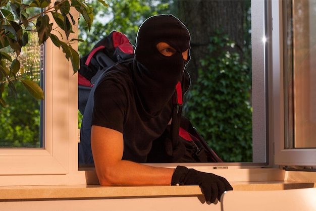 A man wearing a mask looks out of a window.