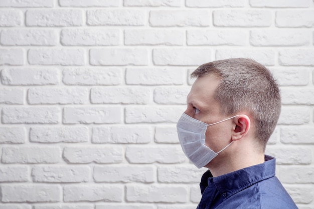 Man wearing a medical mask against the wall