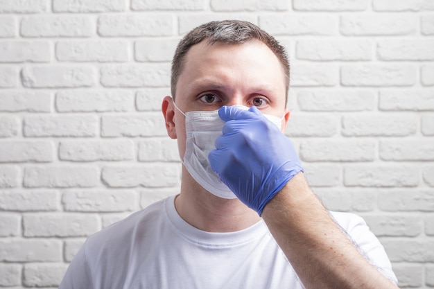 Man wearing a medical mask and protective gloves against the wall