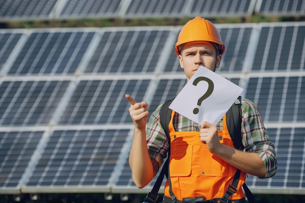 a man wearing an orange helmet holds up a piece of paper with a question mark