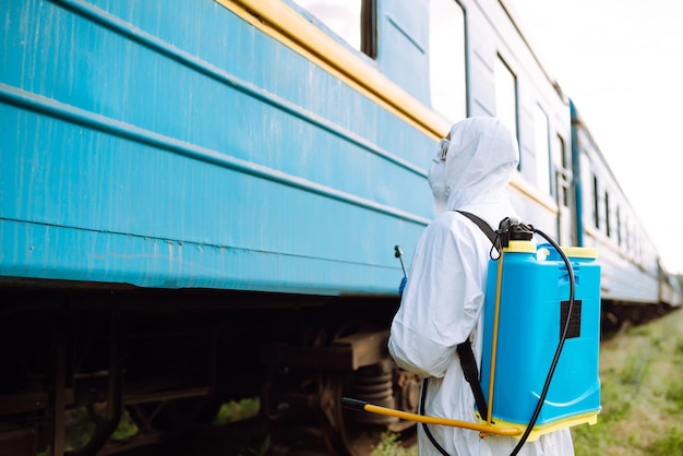 Man wearing protective suit disinfecting public a train