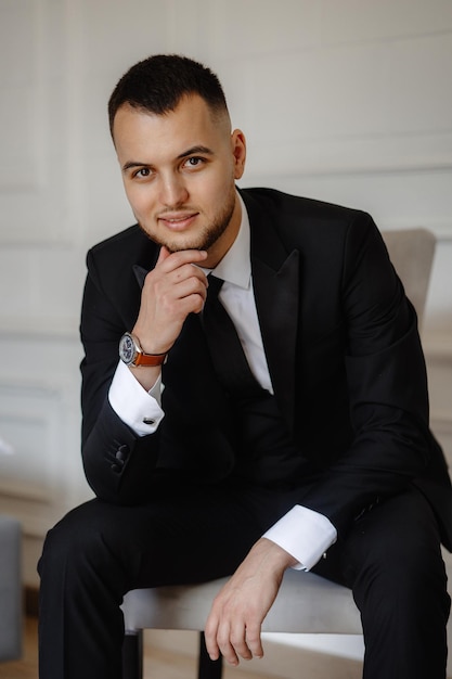 a man wearing a suit and a watch is sitting on a chair