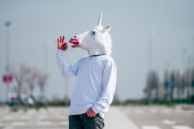 Man wearing unicorn mask making ok gesture with hand