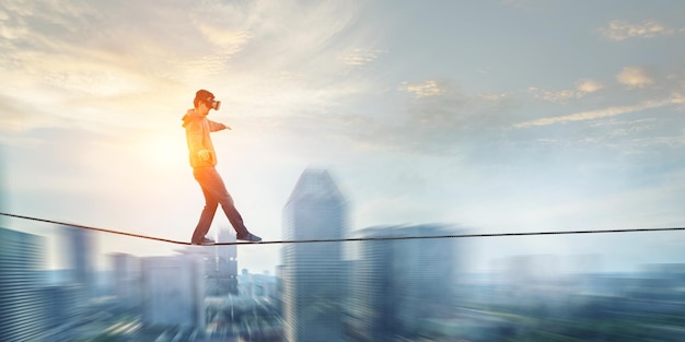 Man wearing virtual reality goggles and balancing on rope. Mixed media