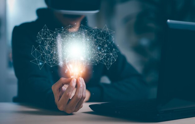 Man wearing VR glasses virtual and holding light bulb with icons and working on the desk, Creativity and innovation are keys to success.Concept  new idea and innovation with energy and power,Metaverse