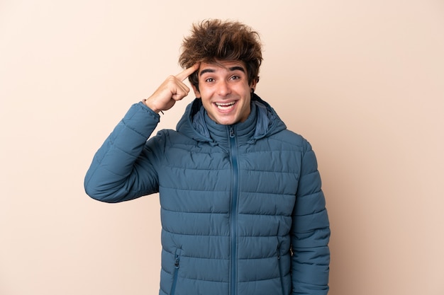 Photo man wearing winter jacket over isolated wall intending to realizes the solution