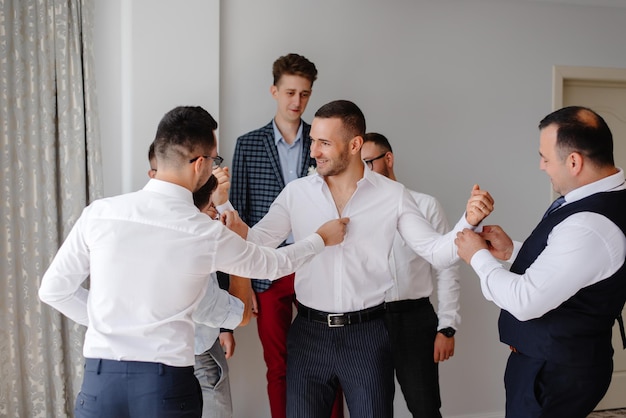 a man wears a shirt with the help of friends