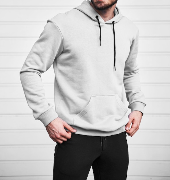 Man wears white hoodie Bearded young sporty guy is standing in light fleece long sleeve sweatshirt