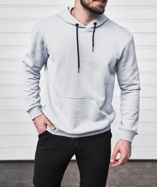 Man wears white hoodie Bearded young sporty guy is standing in light fleece long sleeve sweatshirt