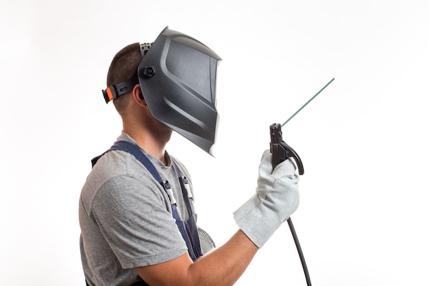 A man in a welding mask, robotic clothes and gloves, holding a wire with a welding electrode.