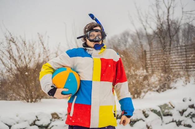 The man went outside in winter in snorkeling equipment and with a beach ball A man dreams of a vacation at sea