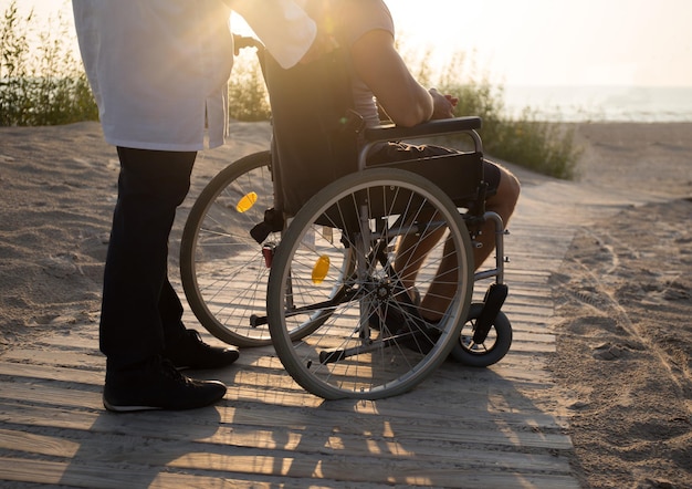 Man in wheelchair and a doctor on a beach.