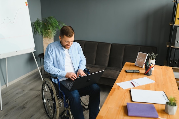 A man in a wheelchair is working in a office The concept of work of people with disabilities