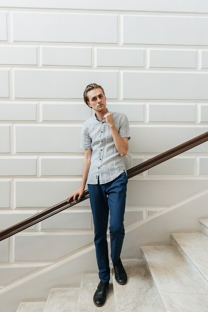 A man in a white plaid shirt and blue trousers poses for advertising men's clothing. Shooting for men's clothing store