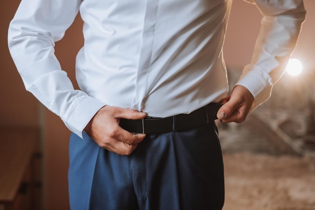 Photo a man in a white shirt and blue pants is adjusting his belt