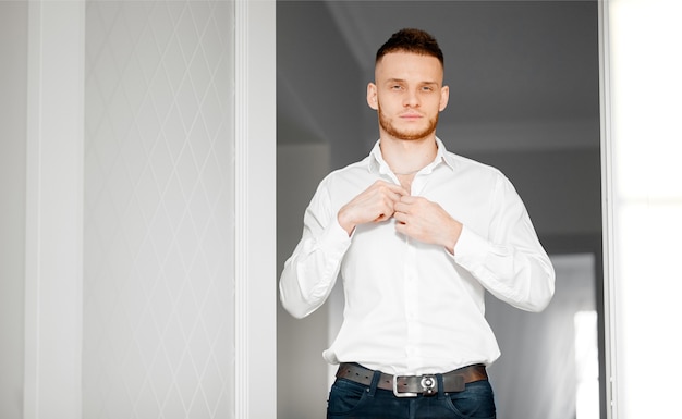 A man in a white shirt in the doorway takes off his shirt