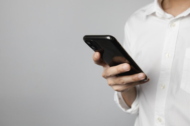 Man in white shirt holding smartphone Focus on the smartphone Copy space