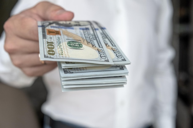 A man in a white shirt holds money counts it and offers it to another