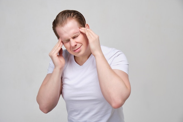 A man in a white shirt massages his head. The concept of headache, migraine.