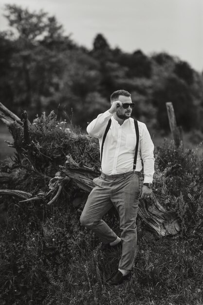 Photo a man in a white shirt and suspenders is posing for a photo in a field