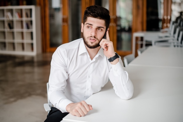 Man in white shirt talking on the phone in the office