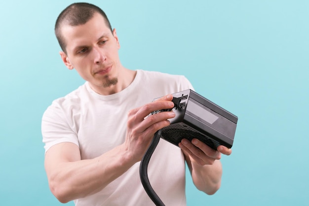 A man in a white tshirt connecting a pin cable to a computer power supply on a blue background Hand Workers Electronic Supply Component Connection Fixing Repairman Unit