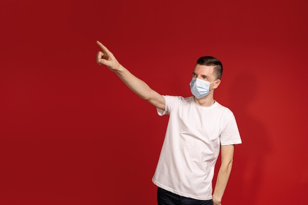 A man in a white Tshirt and protective mask points his finger in the direction of