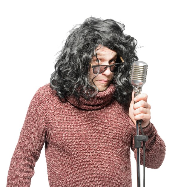 A man in a wig a sweater and sunglasses holding a microphone Isolated