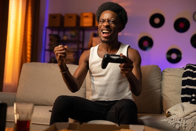 A man wins a round in a console game the man is sitting on the couch in front of the tv with the pad