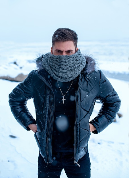 A man in winter on a background of snow in black clothes