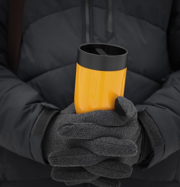 Photo a man in winter clothes holds a yellow thermos