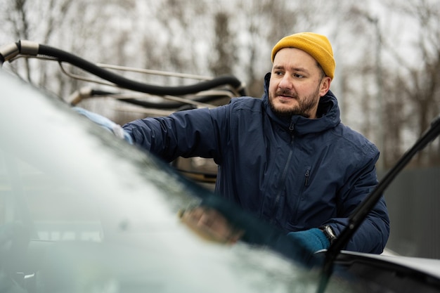 Man wipes american SUV car windshield with a microfiber cloth after washing in cold weather