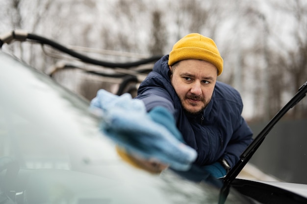 Man wipes american SUV car windshield with a microfiber cloth after washing in cold weather