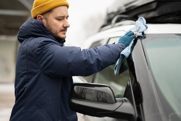 Man wipes american SUV car with a microfiber cloth after washing in cold weather