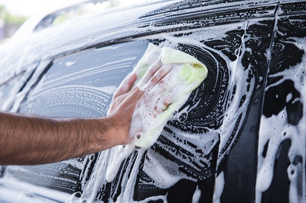 A man wipes the foam on the car with a rag. car wash