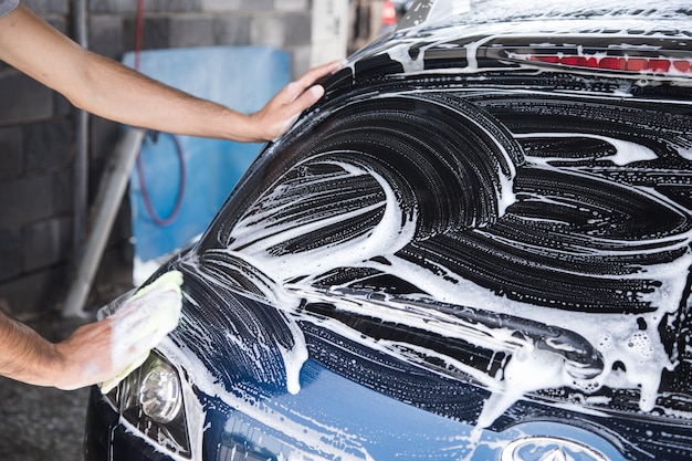 A man wipes the foam on the car with a rag. car wash