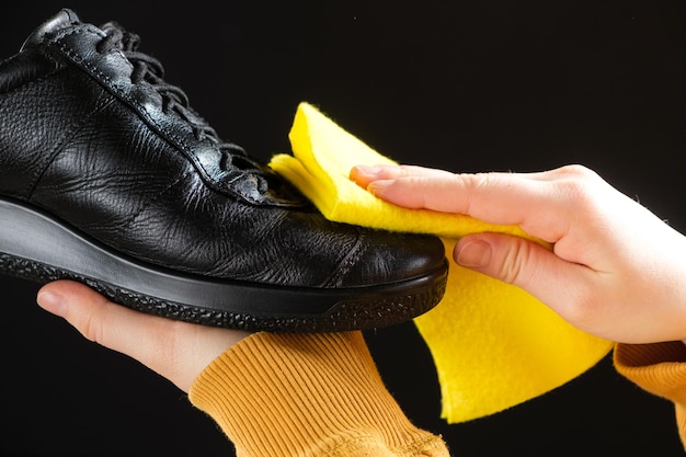 Photo a man wipes leather men's black shoes with a yellow shoe rag cleaning from dust shoe care