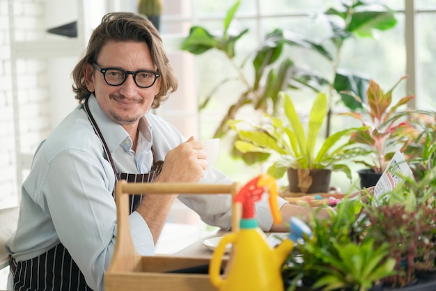 man with apron in greenhouse drinking coffee