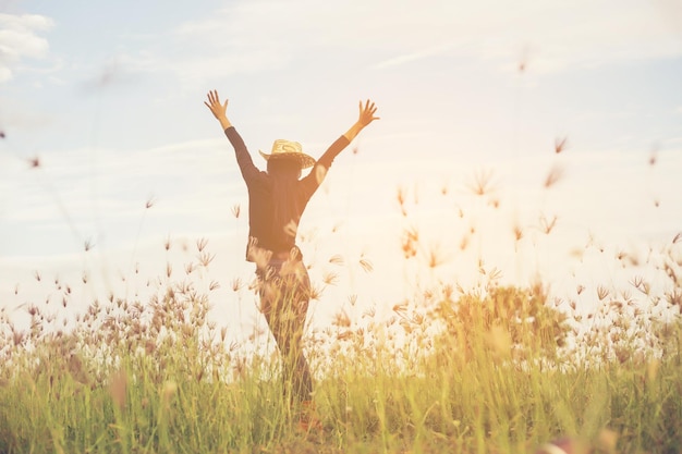 Man with arms raised on field against sky