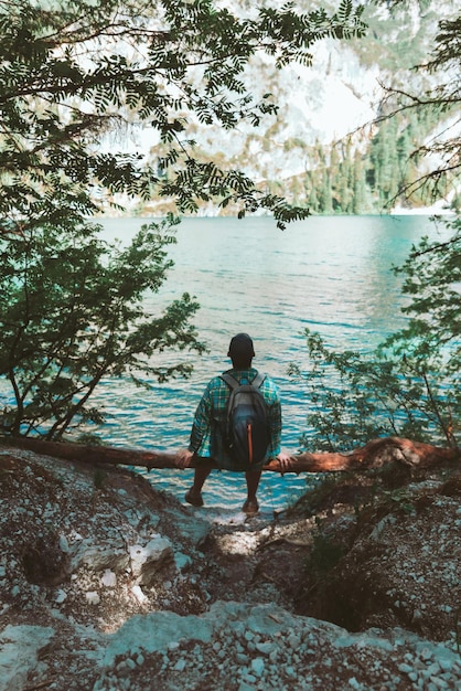 Man with backpack sitting at wood log enjoying water view hiking concept