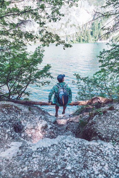 Man with backpack sitting at wood log enjoying water view